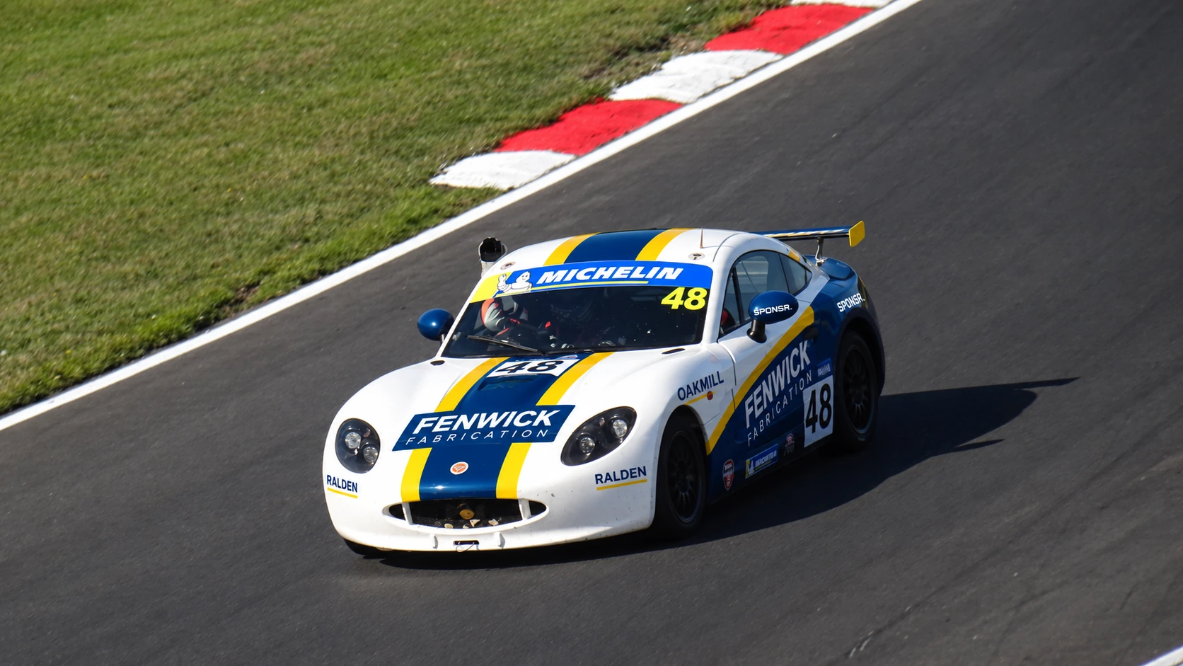 A junior Ginetta on track alone, a young driver's name above the door (SPONSR livery concept).